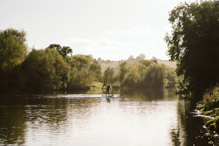 Person paddle boarding along a river